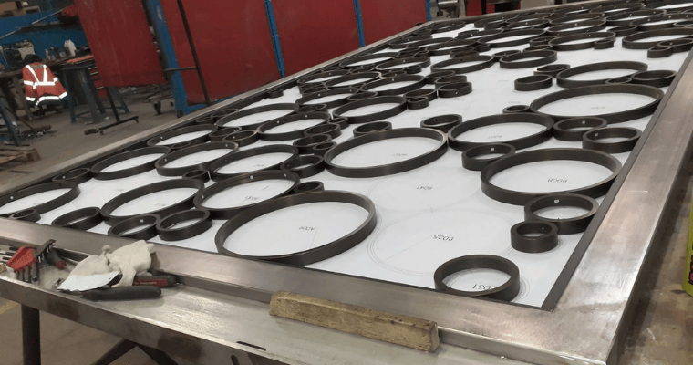 Serrurerie : fabrication en atelier à hossegor d’un panneau métallique sur-mesure avec anneaux (décor circulaire) avant assemblage